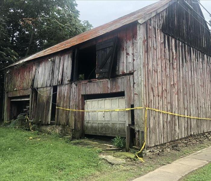 Old worn out barn with fire damage and caution tape around it