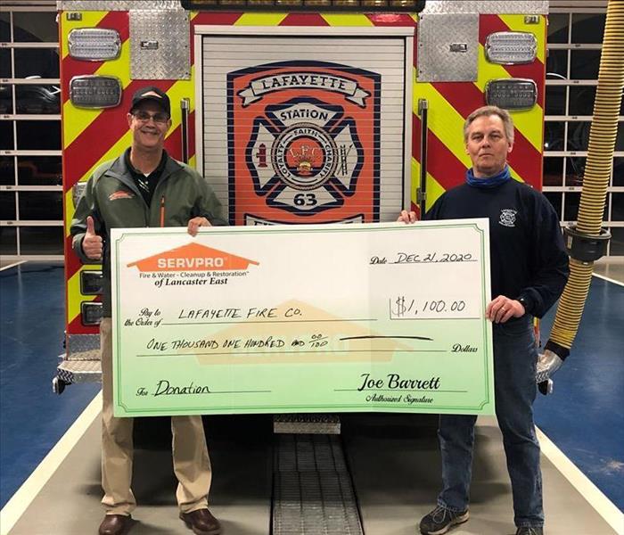 SERVPRO sales manager and fire company employee holding a large display check board