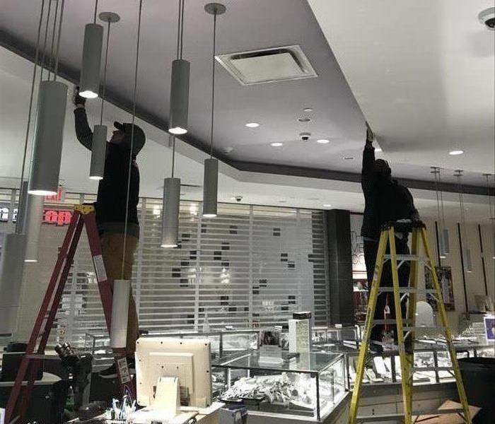 2 men on ladders cleaning in a jewelry store