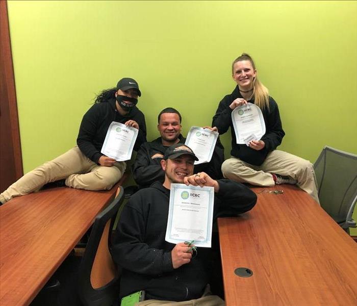 Four employees holding up their certificates